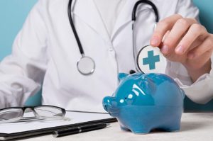 Médico deposita moeda em cofrinho azul em formato de porco, simbolizando economia e segurança financeira para quem busca empréstimo pessoal para emergências médicas.